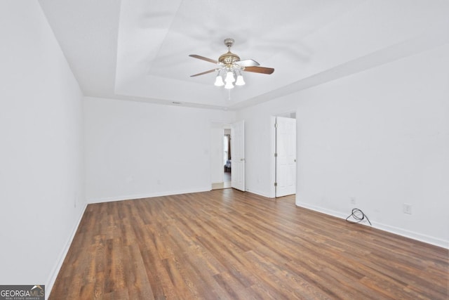 spare room featuring a raised ceiling, dark hardwood / wood-style floors, and ceiling fan