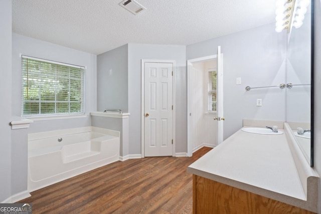 bathroom featuring vanity, hardwood / wood-style floors, a tub, and a textured ceiling