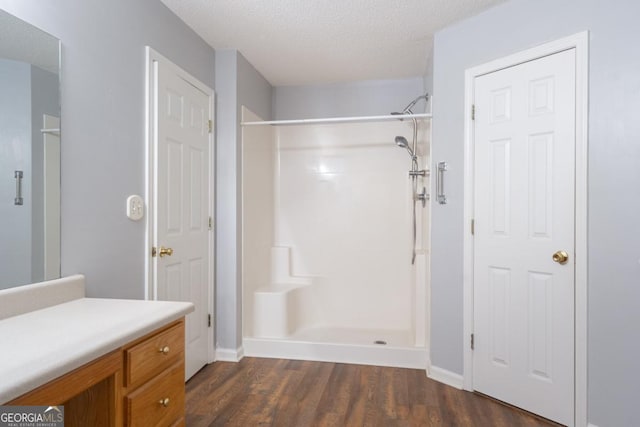 bathroom with vanity, wood-type flooring, a textured ceiling, and walk in shower