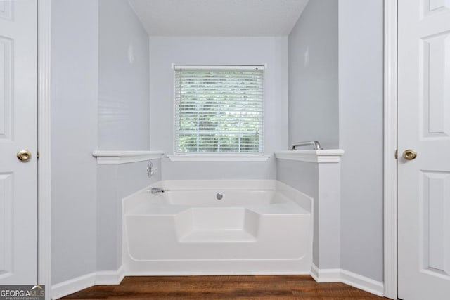 bathroom featuring a tub to relax in, hardwood / wood-style flooring, and a textured ceiling