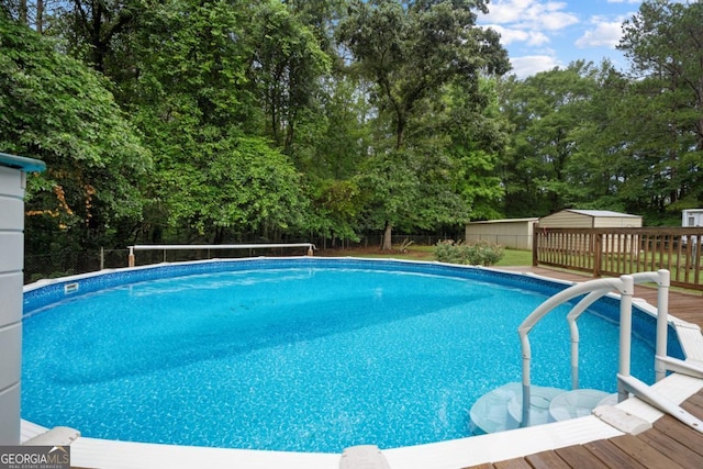 view of pool featuring a wooden deck and a storage unit