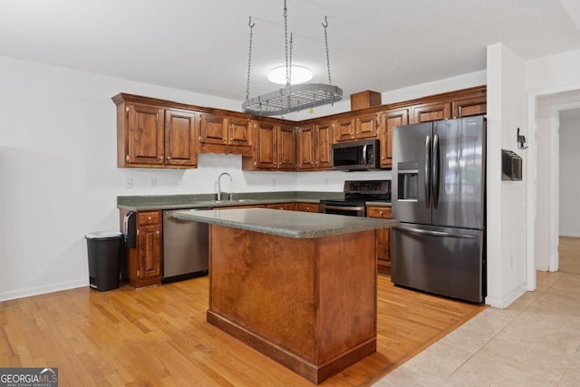 kitchen featuring appliances with stainless steel finishes, a center island, sink, and light wood-type flooring