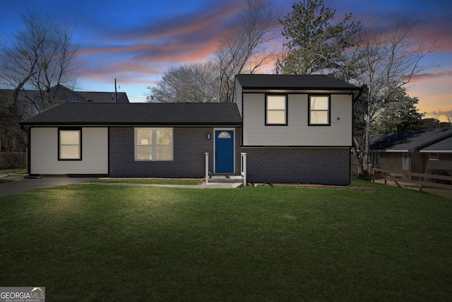 tri-level home with brick siding, a front lawn, and fence