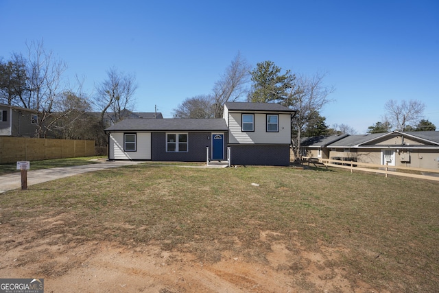 split level home featuring a front lawn, fence, and brick siding