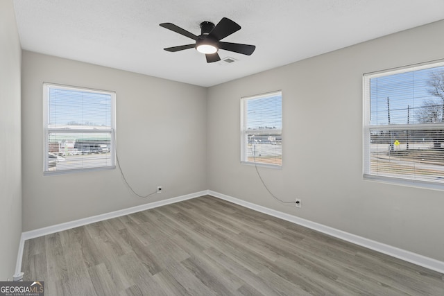 unfurnished room with visible vents, baseboards, a healthy amount of sunlight, and wood finished floors