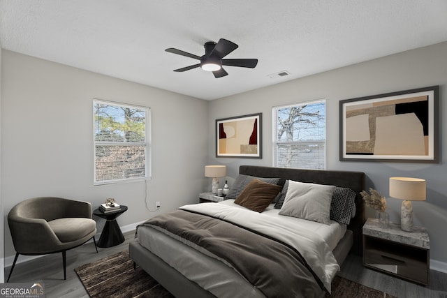 bedroom with visible vents, multiple windows, baseboards, and wood finished floors