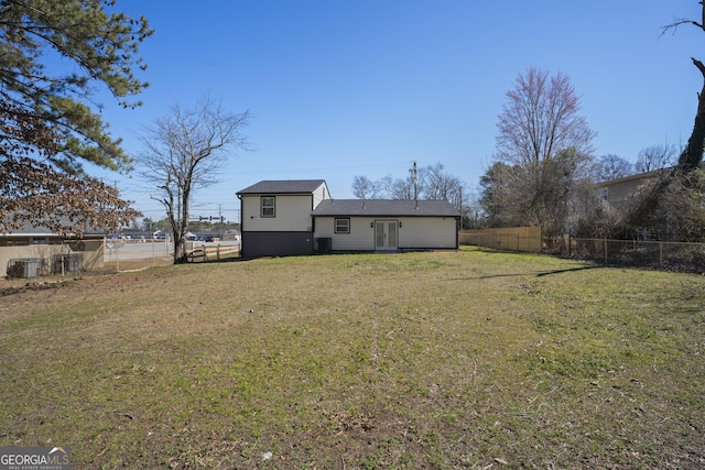 back of house featuring a lawn, central AC unit, and fence