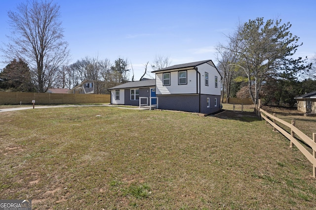 view of front facade with a front yard, fence, and brick siding