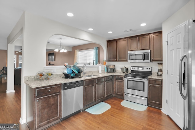 kitchen featuring pendant lighting, sink, stainless steel appliances, and light wood-type flooring