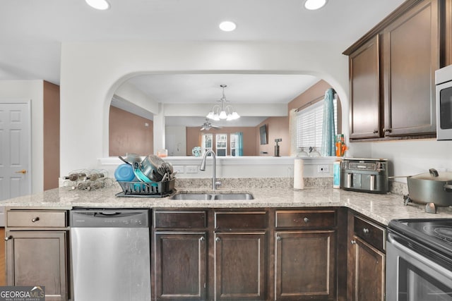 kitchen with dark brown cabinetry, stainless steel appliances, light stone countertops, and sink