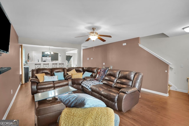 living room featuring wood-type flooring and ceiling fan with notable chandelier