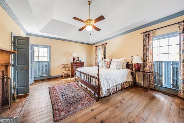 bedroom with ceiling fan, ornamental molding, a raised ceiling, and hardwood / wood-style floors