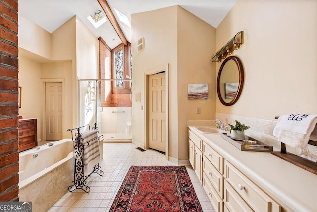 bathroom with high vaulted ceiling, a skylight, independent shower and bath, vanity, and tile patterned floors