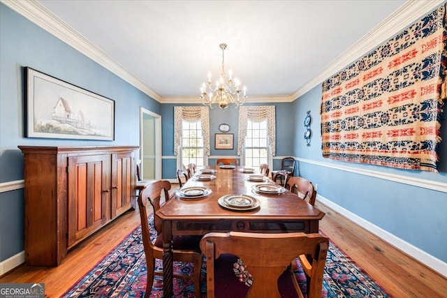 dining area featuring crown molding, a chandelier, and light hardwood / wood-style floors