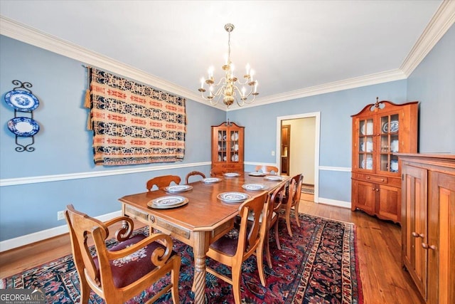 dining area with hardwood / wood-style flooring, ornamental molding, and a chandelier