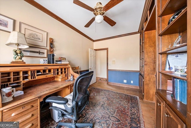 home office featuring dark hardwood / wood-style floors, built in desk, lofted ceiling, ceiling fan, and crown molding