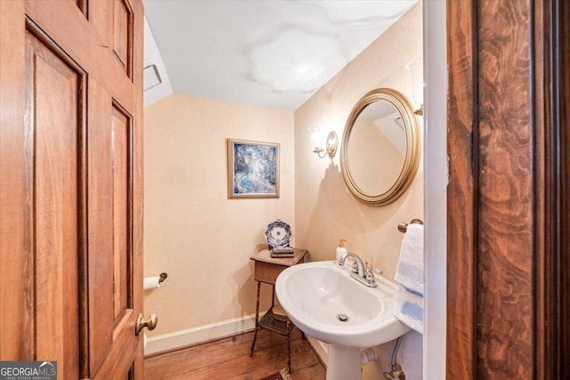 bathroom with vaulted ceiling, sink, and hardwood / wood-style floors