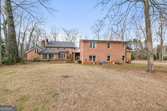 rear view of property with a lawn and central air condition unit