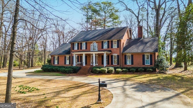 colonial house with a front lawn and covered porch