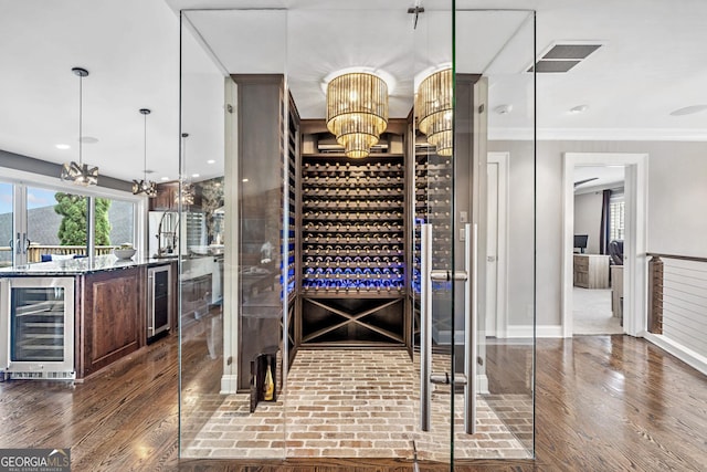 wine area featuring wine cooler, ornamental molding, and dark wood-type flooring