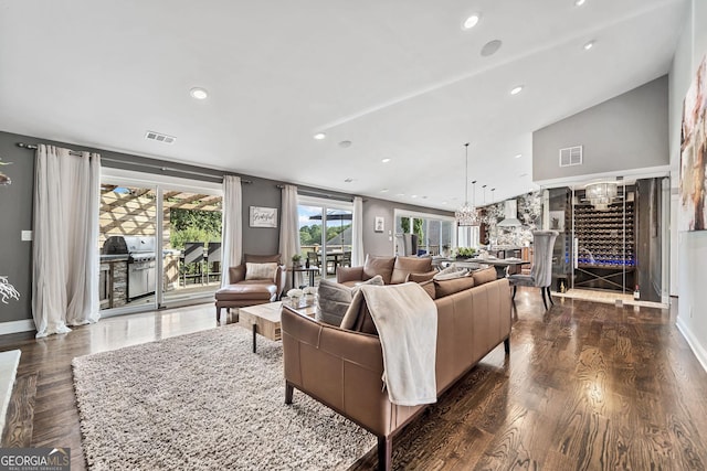 living room with dark hardwood / wood-style flooring, lofted ceiling, and a chandelier