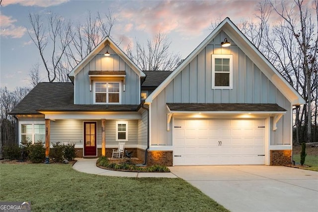 view of front facade with driveway, an attached garage, a front yard, board and batten siding, and brick siding