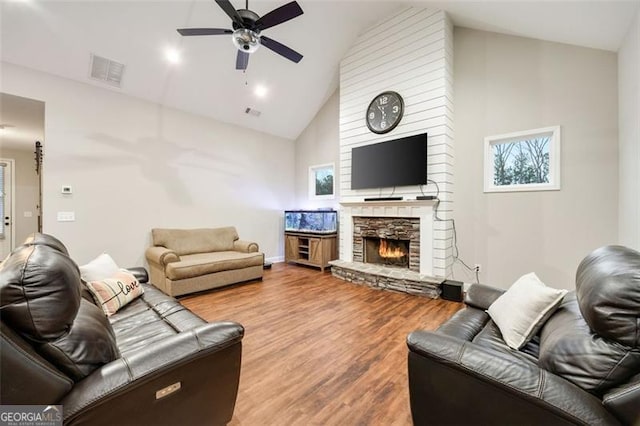 living room featuring high vaulted ceiling, a fireplace, wood finished floors, visible vents, and a ceiling fan