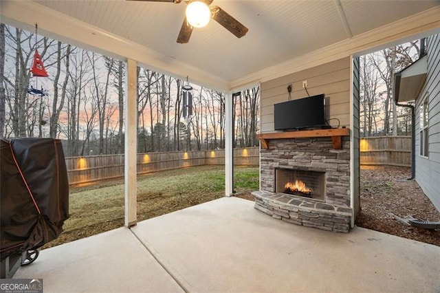 view of patio with an outdoor stone fireplace, a fenced backyard, and a ceiling fan