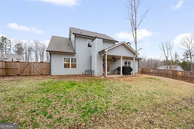 back of house featuring a yard, a fenced backyard, a patio, and a ceiling fan