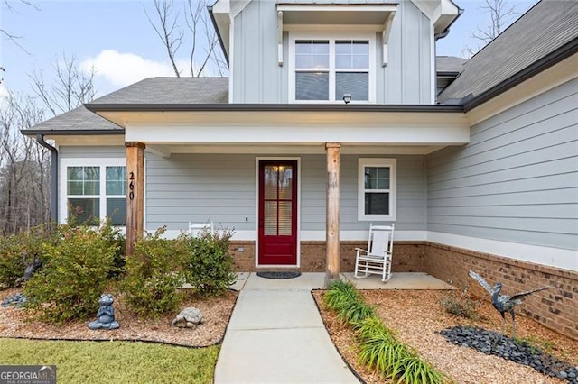 property entrance with covered porch, brick siding, and board and batten siding