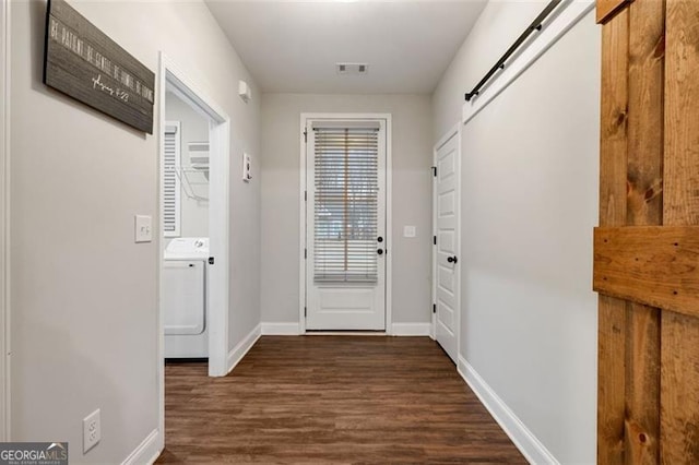 doorway with visible vents, a barn door, dark wood-type flooring, washer / dryer, and baseboards