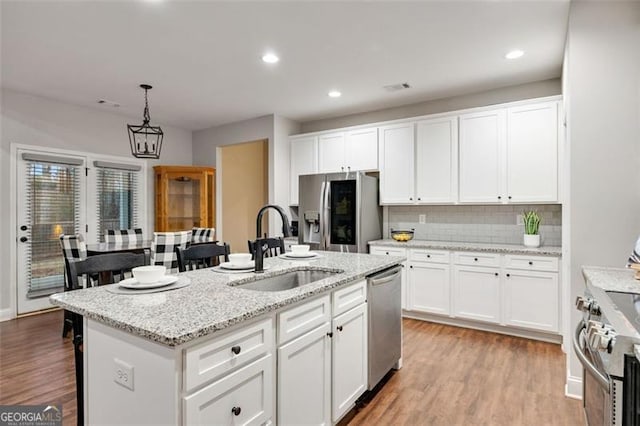 kitchen with light wood finished floors, white cabinetry, stainless steel appliances, and a sink