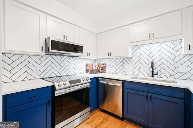 kitchen with tasteful backsplash, appliances with stainless steel finishes, sink, and blue cabinetry