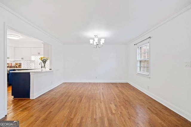 interior space with an inviting chandelier, ornamental molding, and light wood-type flooring