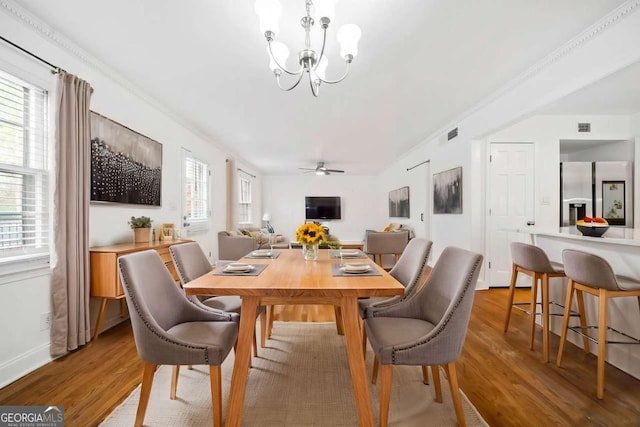 dining room featuring hardwood / wood-style flooring, crown molding, and ceiling fan with notable chandelier