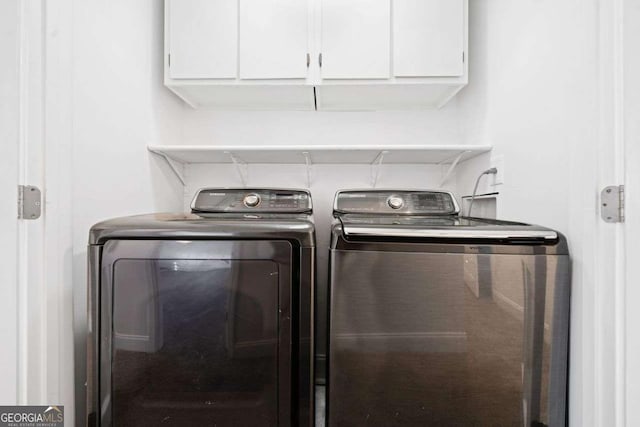 laundry room featuring washer and clothes dryer and cabinets