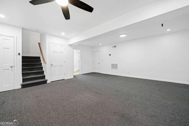 basement with ceiling fan and dark carpet