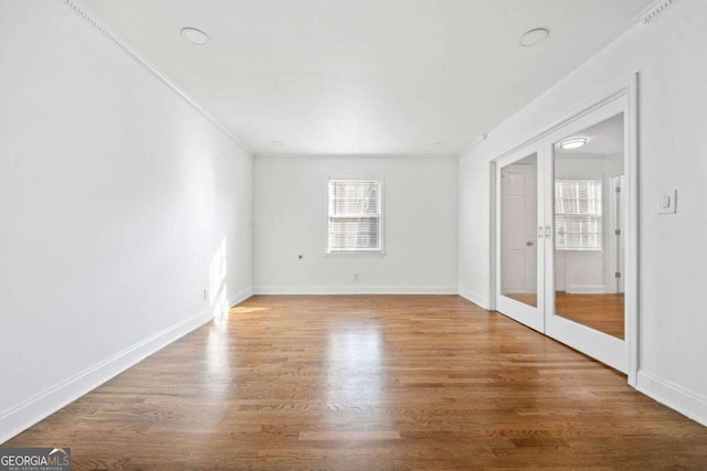 unfurnished room with wood-type flooring, crown molding, and french doors