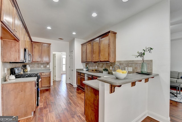 kitchen featuring hardwood / wood-style floors, a breakfast bar area, kitchen peninsula, and range