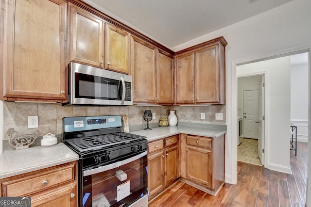 kitchen featuring stainless steel appliances, wood-type flooring, and backsplash