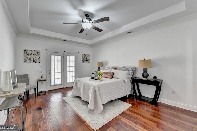 bedroom featuring a raised ceiling, crown molding, ceiling fan, and dark hardwood / wood-style flooring