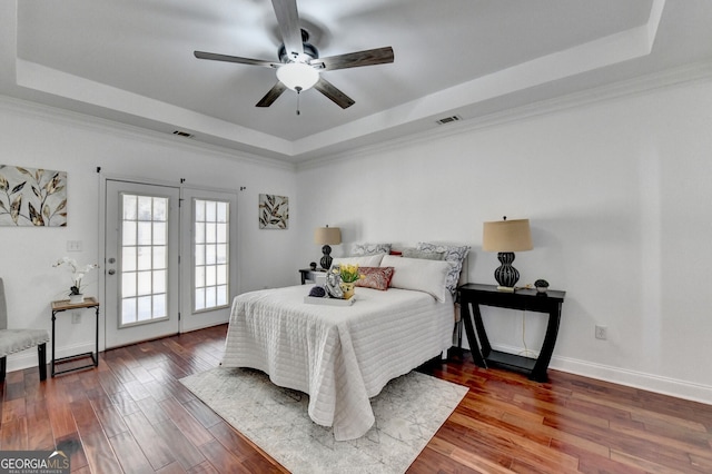 bedroom with hardwood / wood-style flooring, ornamental molding, and a tray ceiling