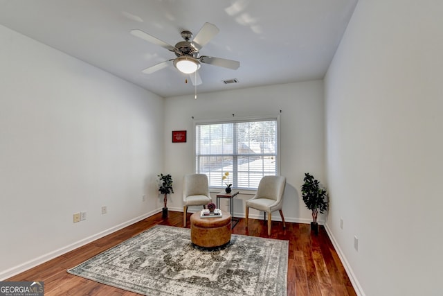 living area with dark wood-type flooring and ceiling fan