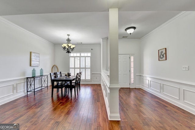 dining room with ornate columns, crown molding, a notable chandelier, and dark hardwood / wood-style flooring