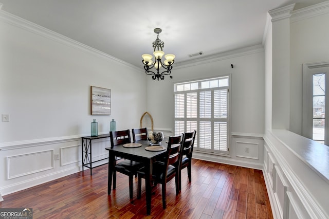 dining space featuring dark hardwood / wood-style flooring, crown molding, and a chandelier