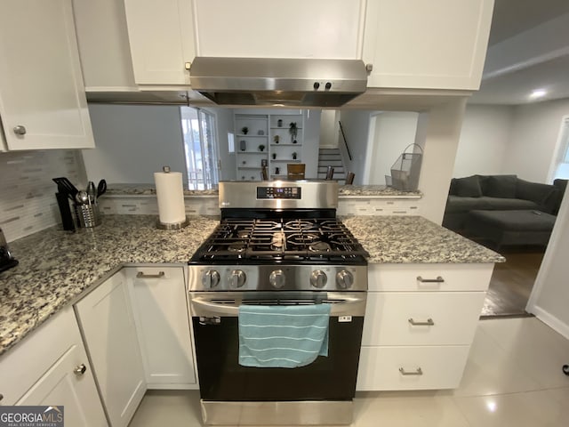 kitchen with white cabinetry, gas stove, light stone countertops, and backsplash