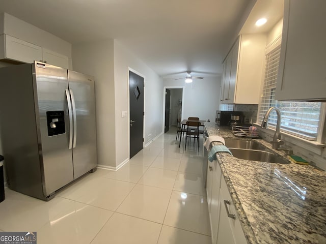 kitchen with sink, white cabinetry, stainless steel fridge with ice dispenser, light tile patterned floors, and stone counters