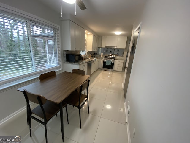 kitchen with sink, light tile patterned floors, stainless steel appliances, light stone countertops, and white cabinets