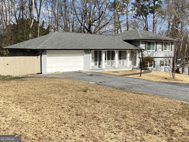 split level home with a porch, a garage, and a front lawn