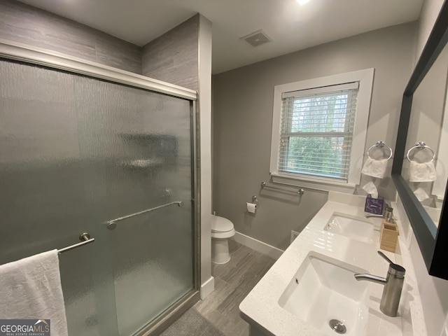 bathroom with toilet, hardwood / wood-style floors, vanity, and a shower with shower door